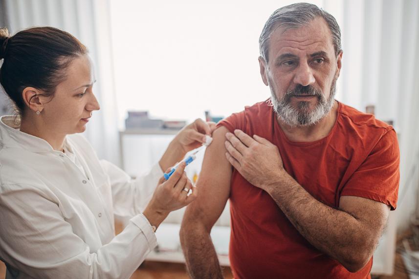 A man in a red shirt receives his flu shot