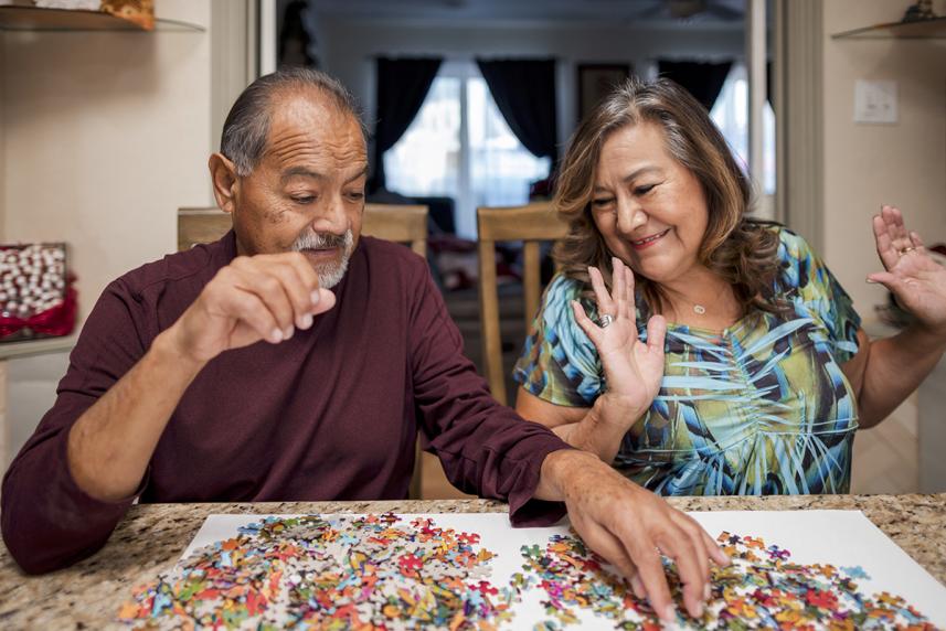A couple sitting at a table, working on solving a puzzle