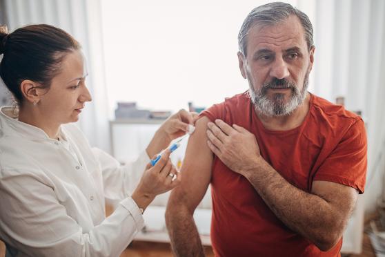 A man in a red shirt receives his flu shot